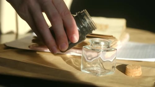 Black Ink Being Poured into Small Glass Jar