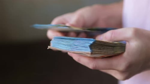 Hands Fanning Through Stack of Colorful Paper Money