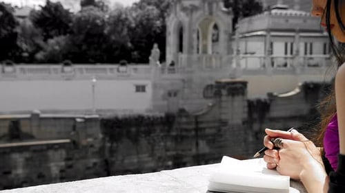 Pretty girl journalling, writing down notes in notebook. Woman in purple dress writing before