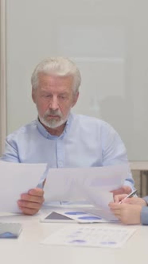 Senior Man Discussing Charts and Graphs at Workplace