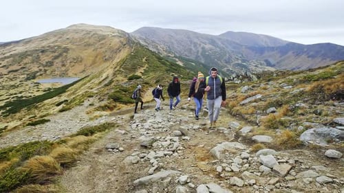 Group Hiking Along Mountain Ridge on Cloudy Day