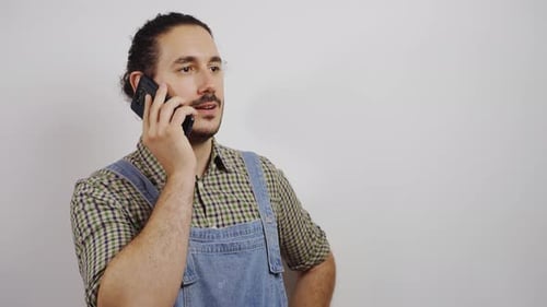 Young Adult Talking on Phone Wearing Overalls