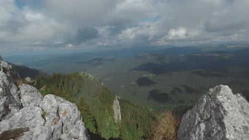 Wide angle panning-right camera movement revealing a mountain landscape from above standing along si