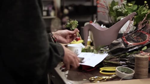 Person decorating gift with fresh greenery