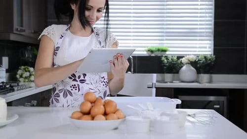 Woman in Kitchen Baking with a Tablet