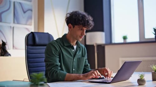 Enthusiastic Young Man Celebrates Success at Desk