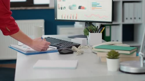 Adult Writes on Charts and Graphs at Desk