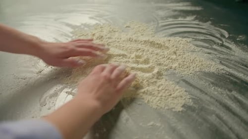 professional chef throws flour on table stirs it before preparing bread pastry in bakery