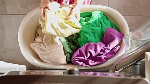 Woman Loading Colorful Laundry into Washing Machine