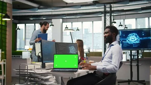 Technician Using Mockup Laptop Next to Office Coworkers Developing Applications