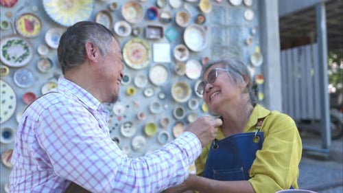 In the pottery workshop, an Asian retired couple is engaged in pottery making and clay painting