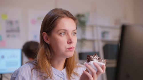 Grupo de hombres de negocios y mujeres comen rosquillas mientras trabajan en la oficina.