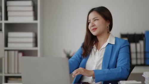 Smiling Woman Stretching at Her Desk in Office