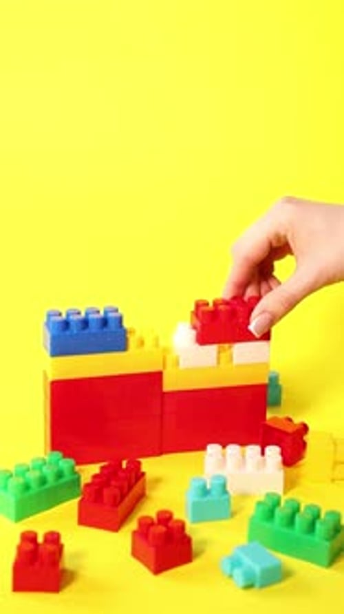 Mujer con bloques de construcción coloridos sobre fondo amarillo, primer plano