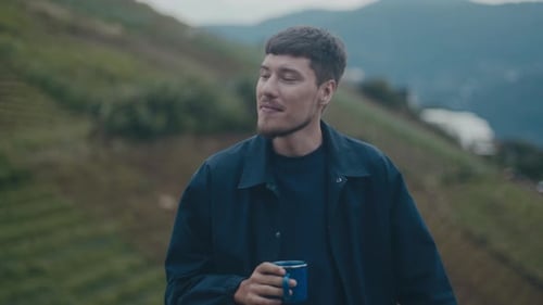 Man Drinking Refreshment on Scenic Hillside