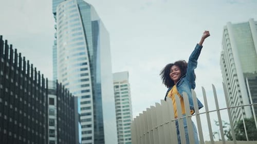 Happy joyful young tourist African American woman open arms enjoy in the center of a city urban