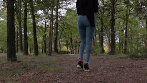 Girl with long legs walking on a forest path low-angle shot. Young female model in the woods.