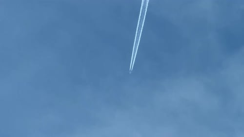 Contrails in Blue Sky from Flying Airplane, Seen from Cockpit Below.
