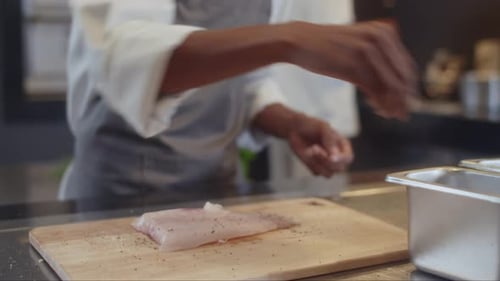 Sous Chef Adding Pepper to Fish Cooking at Restaurant