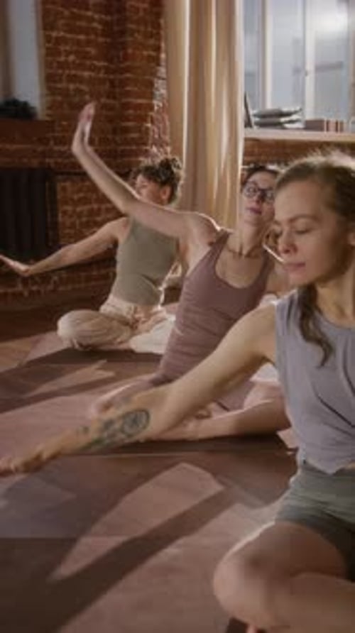 Caucasian Girls Doing Seated Side Stretch in Loft Yoga Studio