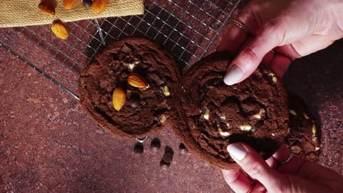 Hand Breaking Soft Cookie With Almonds Showing Fresh Baked Center