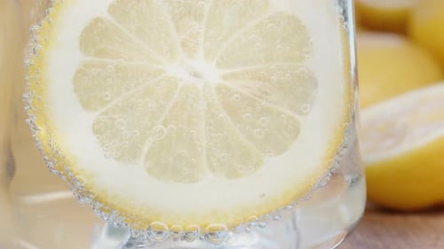 A slice of lemon in a glass of lemonade. Close-up bubbles.