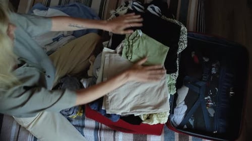 top view of a woman packing things in a suitcase for vacation