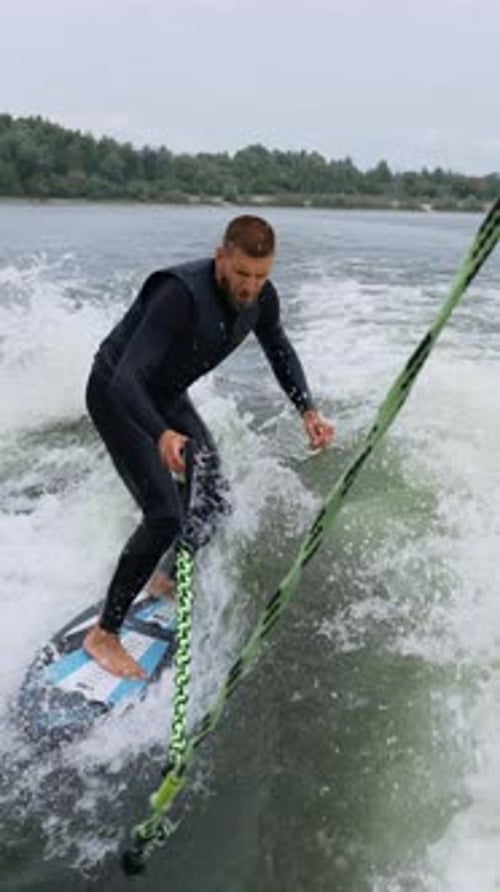 Young Man Wake Surfing on Lake on Cloudy Day