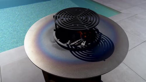 Fire burning inside metal brasero with circular grill top