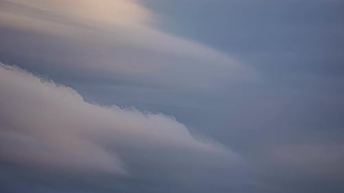 Zeitrafferaufnahme von Wolken, die sich im Hintergrund über den blauen Himmel bewegen.