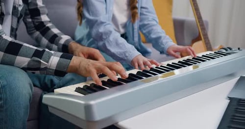Close-up of Hands of Father and Daughter Playing Electric Piano Together at Home. Weekend Activity
