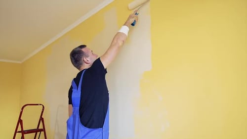 Reforma de quarto na casa. Tinta sendo aplicada na parede por um trabalhador profissional.