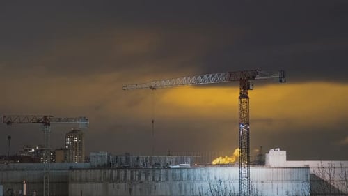 Cranes at a Construction Site Work at Night Time Lapse