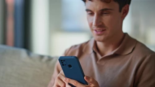Young Man Using Smartphone While Relaxing Indoors