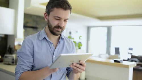 Man with Beard Using Tablet in Modern Home