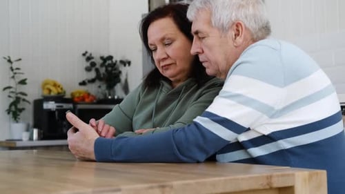 Senior Couple Looking at Phone in Bright Kitchen