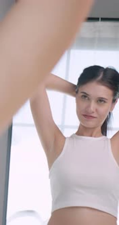 Woman Puts Hair in Ponytail in Mirror