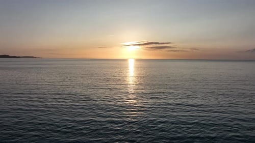Aerial Drone Shot Flying Over Calm Sea Towards a Beautiful Sunset