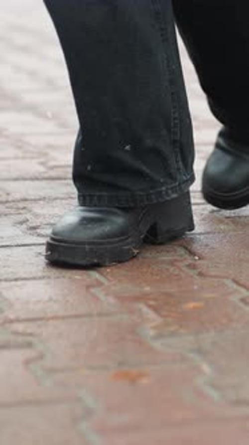 Foot of Person in Black Boots Turning on Wet Ground After Rain