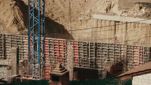 Grue de construction soulevant des coffrages pour couler des murs en béton