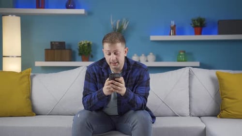 Young Adult Man Looking at Phone and Crying