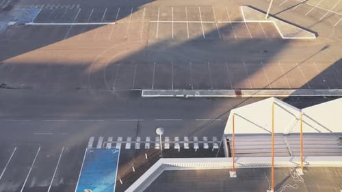 Empty massive parking lot near shopping building, aerial fly over shot