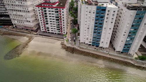 Aerial shot from top to bottom through the beach towards the city buildings