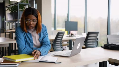 Afroamerikanischer Student macht sich während des Studiums in der Bibliothek Notizen
