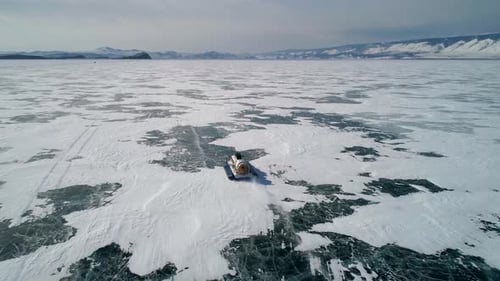 Aerial View on the Hovercraft Driving on Cracked Snowy Ice of Baikal Drone Follows the Vehicle