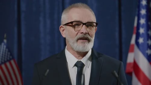 Man Speaks at Podium with Flags