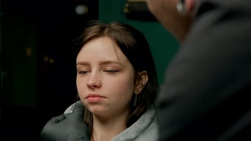 Interior de un estudio de piercings: el maestro de piercings hace un piercing para una niña, piercing para el tabique nasal