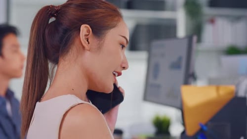 Asian happy businesswoman talking on smartphone and working in office.