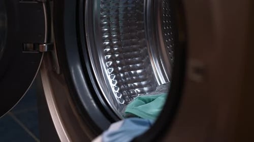 Top View of Male Loading Dirty Clothes Into Modern Washing Machine in Home Laundry Room Symbolizing