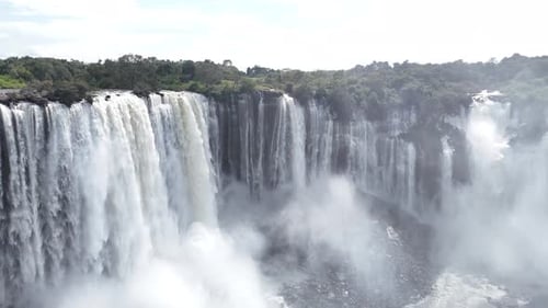 Massive Cascading Waterfall Plunging Into a Misty Tropical Jungle Canyon